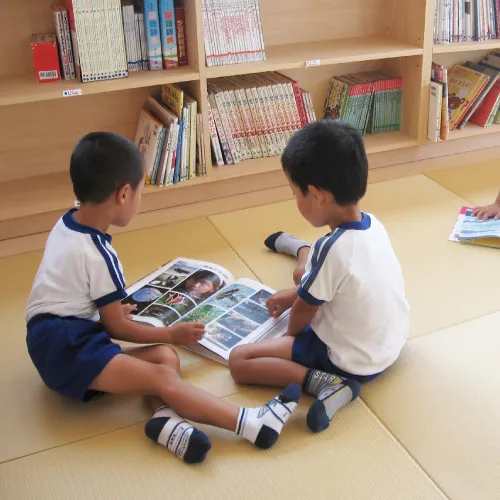 畳の図書室で図鑑を読む園児