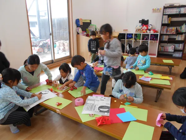 預かり保育で、先生と一緒に机で工作をする子どもたち